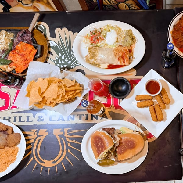 Overhead view of a table laden with various Mexican dishes, chips, beer, and sauces at Casa Jalisco.