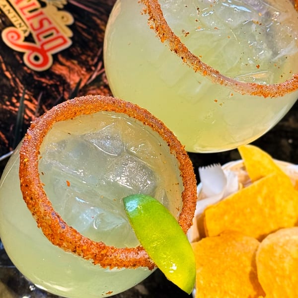 Two Casa Jalisco margaritas with chili-lime rims and a lime wedge, next to tortilla chips.